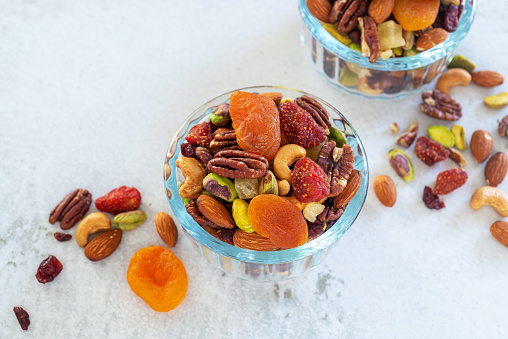 mixed nut and dried fruit in glass bowl on white table background.