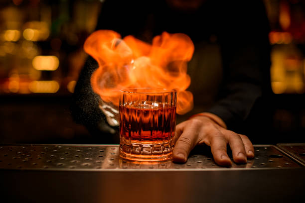istock front view of old-fashioned glass with cold alcoholic drink on bar and fire flame at it 1394239695