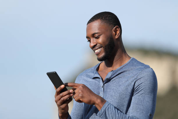 istock Happy man with black skin using smart phone outside 1394241465