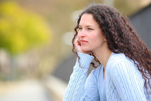 Serious pensive woman in a park looking away