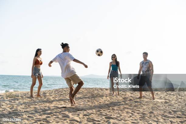 Group Of Asian Young Man And Woman Play Soccer On The Beach Together Attractive Friend Traveler Feel Happy And Relax Having A Football Game While Travel For Holiday Vacation In Tropical Sea Island Stock Photo - Download Image Now