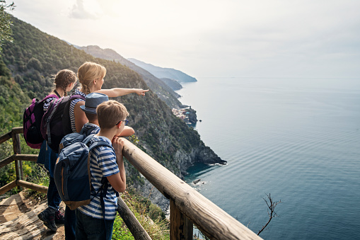 Family hiking in trails of Cinque Terre - a UNESCO World Heritage Site. The family walking on a trail from Vernazza to Monterosso al Mare. They are standing on a high path and lookingat the magnificient view of the Cinque Terre coast. Vernazza is visible in the background.
Nikon D850