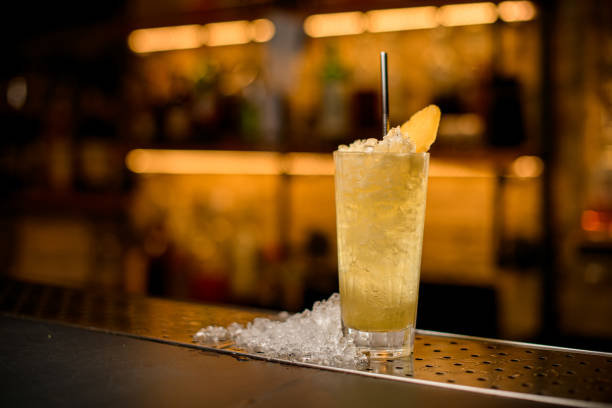 istock Great front view on cocktail glass with ice garnished with pineapple slice and steel drinking straw. 1394243132