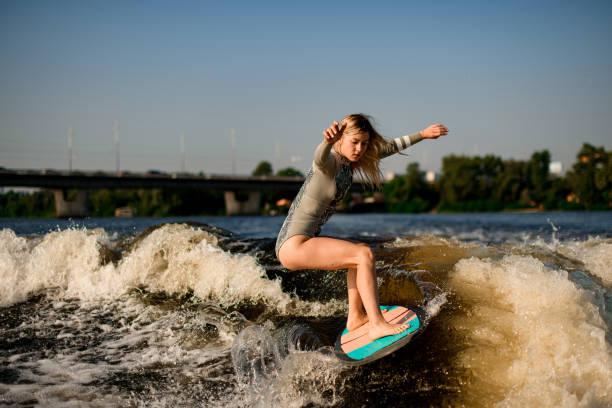 istock active flexible woman energetically balancing on great splashing wave on wakesurf board. 1394247457