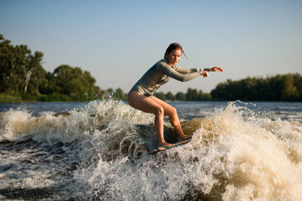 istock active flexible woman skillfully balancing on great splashing wave on wakesurf board. 1394247677