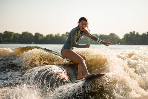 donna bagnata sorpresa wakesurfer cavalcando l'onda spruzzante in una giornata calda - wakeboarding foto e immagini stock