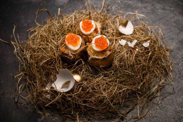 great view of boiled eggs stuffed with red caviar and serving in golden shell on decorative hay