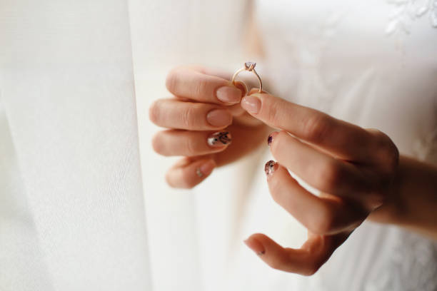istock beautiful bride holds a wedding ring with a diamond in her hands 1394250306