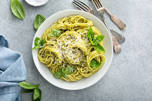 Basil pesto spaghetti pasta with fresh basil leaves, olive oil and parmesan
