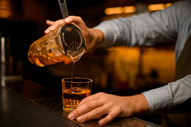istock male bartender hand gently holding mixing cup with cocktail and strainer and pours bright beverage into glass 1394252225
