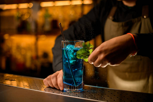 istock beautiful view on clear glass with blue cold drink on bar and the bartender decorating it with fresh green mint leaves 1394252491