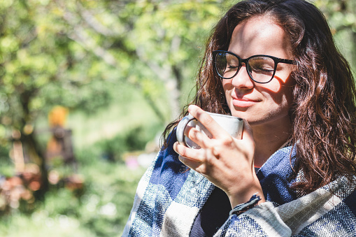 Happy smiling adult 34 years old woman in glasses enjoying coffee in morning outdoors.