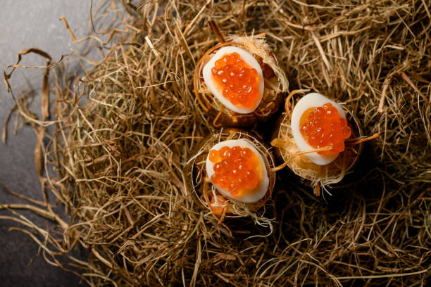 Close-up top view of eggs stuffed with red caviar and served on decorative hay