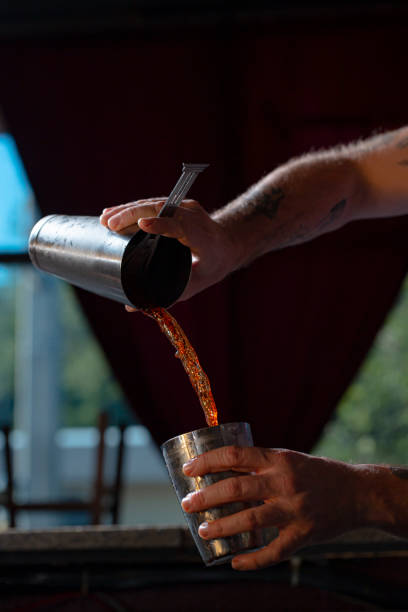 istock Bartender pouring red cocktail into tin - close and conservative 1394256026