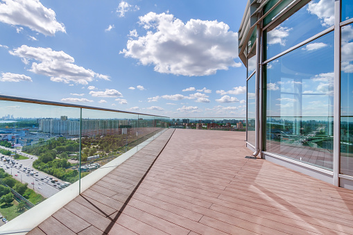 Panoramic open space balcony skyline and glass buildings view with empty wood floor sunny blue cloudy sky background. Sustainable lifestyle concept.