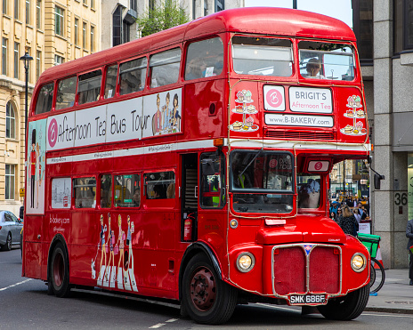 Double Decker Bus on The Strand, London. People are walking along the sidewalk and registration plates for the bus and a taxi are visible