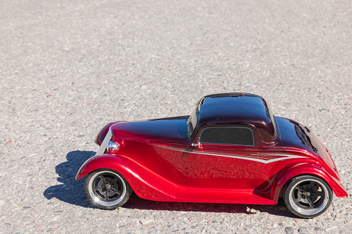 Close up side view of radio-controlled small-sized model of old passenger car isolated on pavement. Sweden.