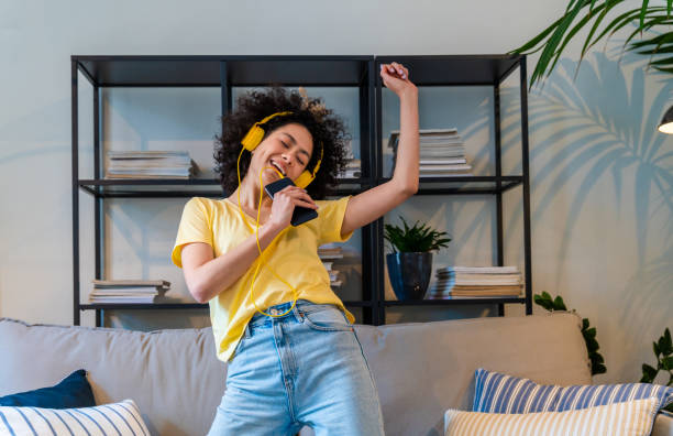 Beautiful latino woman at home Beautiful latino young woman at home - Pretty south american with curly hair female portrait, lifestyle and domestic life scene listening stock pictures, royalty-free photos & images