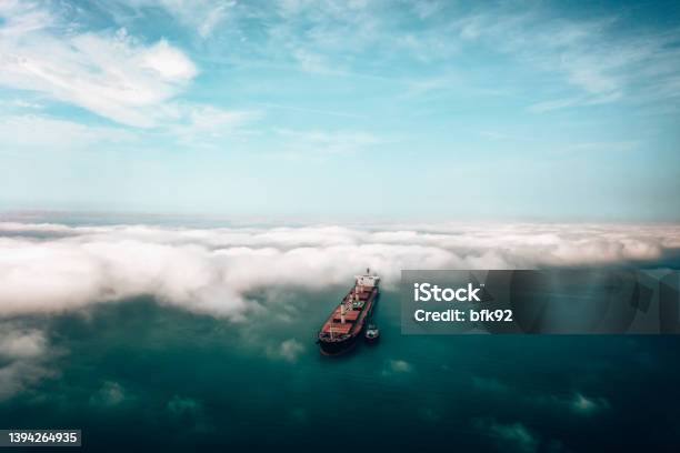 Aerial View Of Cargo Ship Approaching Port With Tugboat Stock Photo - Download Image Now