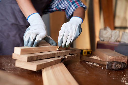 Business woman working as carpenter in a small carpentry workshop. Female carpenter working in carpentry shop with pencil drawing sign on plank.