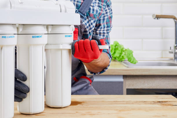 istock Plumber installs or change water filter. Replacement aqua filter. Repairman installing water filter cartridges in kitchen. Installation of reverse osmosis water purification system. 1394265275