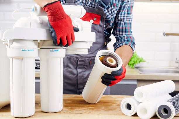 istock Plumber installs or change water filter. Replacement aqua filter. Repairman installing water filter cartridges in kitchen. Installation of reverse osmosis water purification system. 1394265280