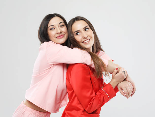 istock two beautiful girls dressed in pajamas hugging and smiling 1394268103
