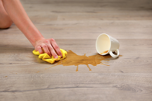 A cup of coffee fell on laminate, coffee spilled on floor.