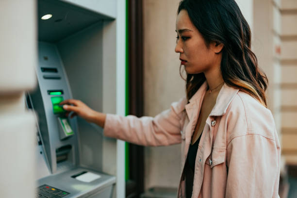 istock Woman using ATM machine outdoors 1394269602