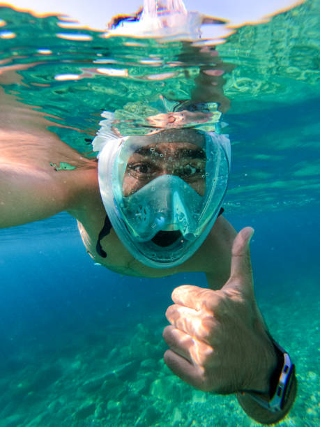 Man snorkeling in the sea with a full face snorkel mask stock photo