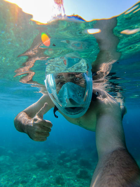 Snorkeling man with thumb up and action camera. stock photo