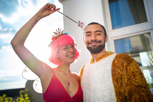 summer party: Young woman in elf costume with pink wig enchants a young man in bear costume