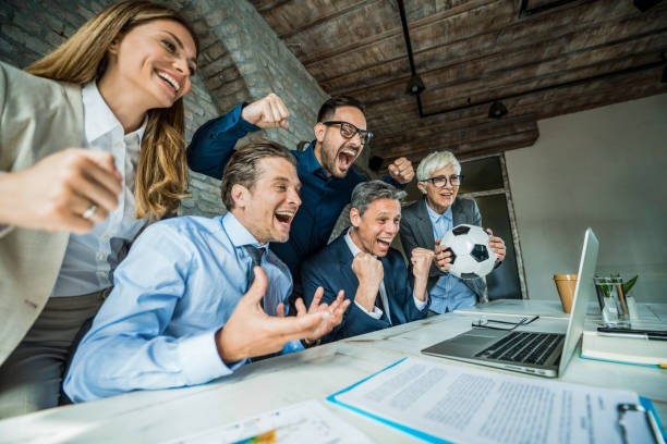 Cheerful business people cheering while watching their sports team on computer in the office.