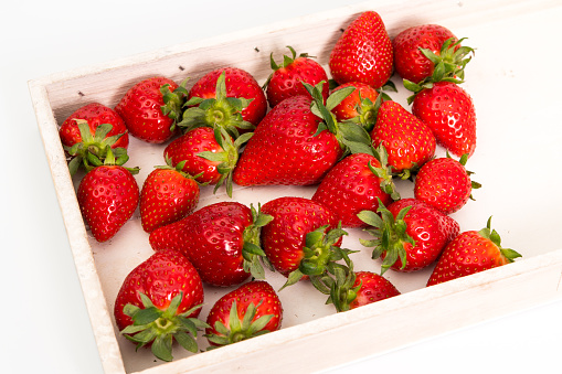 A number of strawberries on a wooden tray.