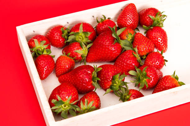istock White tray with strawberries on red background 1394279312
