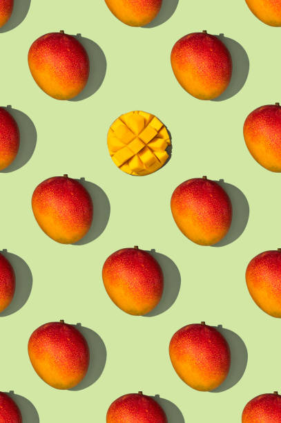 Patterned composition of sweet tasty mango lying side by side on a green background, top view Patterned composition of sweet tasty mango lying side by side on a green background, top view mango fruit photos stock pictures, royalty-free photos & images