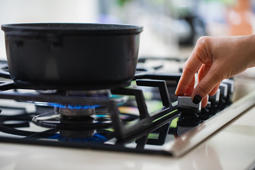 Woman hand, Stove. Cook stove. Modern kitchen stove with blue flames burning