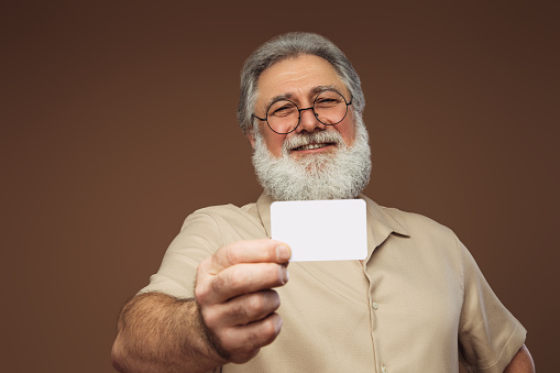 Portrait of a real happy old man holding business card