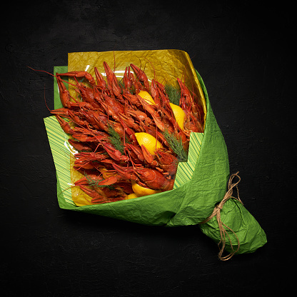 Bouquet of a large amount of boiled appetizing crayfish with lemon slices and dill on a black background