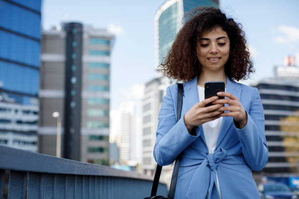 istock Young smiling businesswoman typing text message on her way to work 1394289097