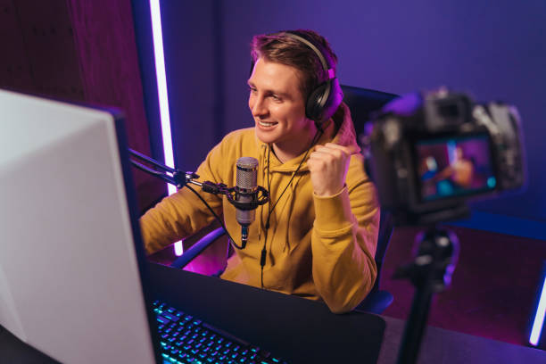 istock Smiling vlogger cyber sportsman has video stream while playing computer games at home 1394291864
