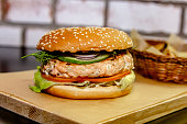 A delicious homemade grilled salmon burger with tomato and lettuce on a bun