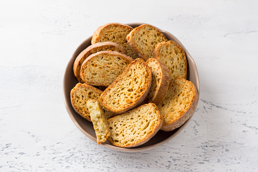 Ceramic bowl with traditional Italian biscotti cheese croutons on a light gray background, top view. Delicious homemade food