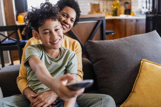 istock Mother and son sitting on the couch and watching TV 1394295784