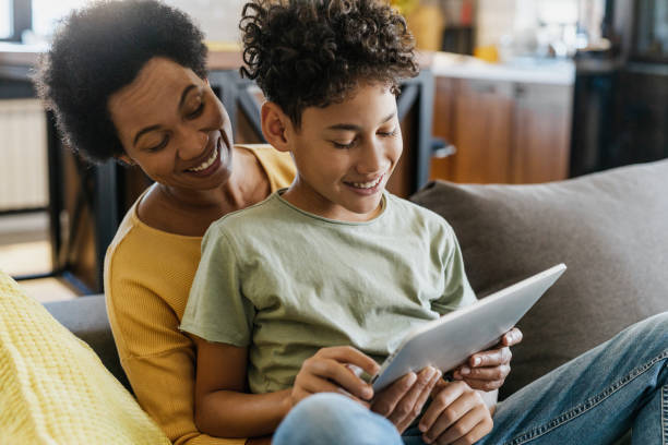 African-American mother and her teenage son using digital tablet stock photo