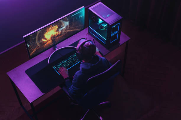 Top view of man pro gamer playing online video game at home Top view of professional cyber sportsman in headphones playing shooter video game on his powerful gaming PC in dark neon room at night. Pro gamer participates in online esport tournament. Cyber sport gaming chair photos stock pictures, royalty-free photos & images