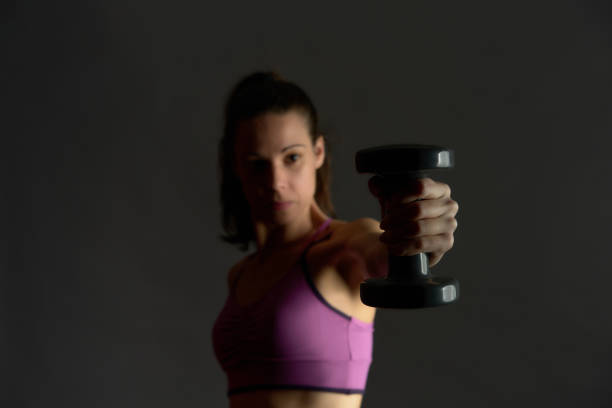 woman training with weights on gray background and dark dramatic style