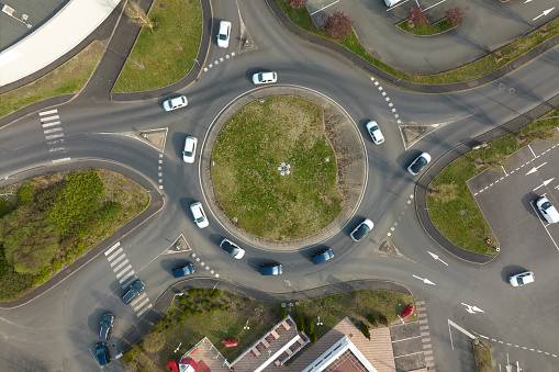 Aerial view of road roundabout intersection with fast moving heavy traffic. Urban circular transportation crossroads.