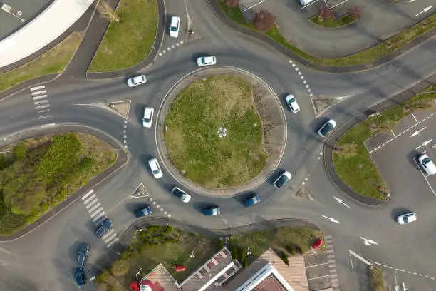 Aerial view of road roundabout intersection with fast moving heavy traffic. Urban circular transportation crossroads.