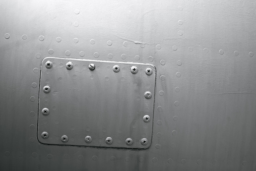 Close-up gray airplane metal panel with patch, background texture, rivets, dots, line